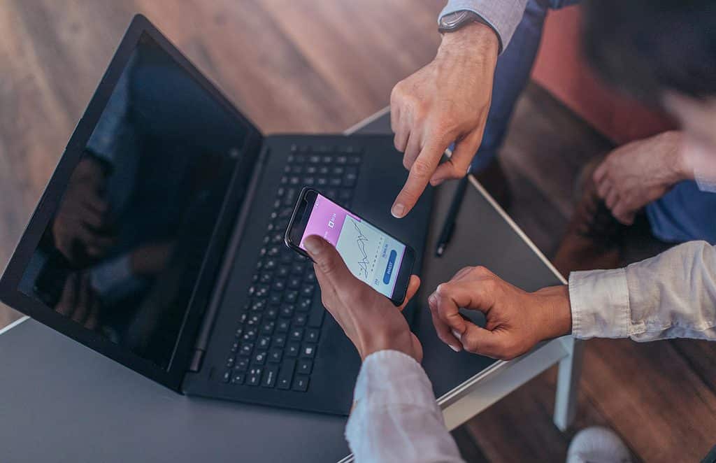 A close up shot of businessmen looking in a phone and having convrsation.