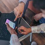 A close up shot of businessmen looking in a phone and having convrsation.