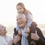 Grandparents And Granddaughter Walking On Winter Beach.