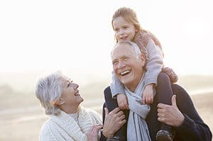 Grandparents And Granddaughter Walking On Winter Beach.