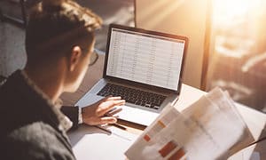 Young banking finance analyst in eyeglasses working at sunny office.