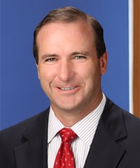 A professional headshot of Tom Doud.