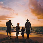 A vacation concept of a happy family with tree kids walk at sunset beach.
